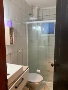 a bathroom with a toilet and a glass shower at Ótimo Apartamento Frente ao Mar em Mongaguá in Mongaguá