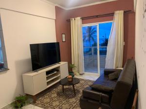 sala de estar con sofá y TV de pantalla plana en Ótimo Apartamento Frente ao Mar em Mongaguá, en Mongaguá