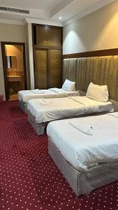ARAEK AL KHLOOD HOTEL في مكة المكرمة: غرفة في فندق بثلاث اسرة في غرفة