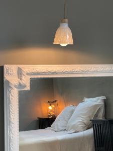 una cama con una cabecera blanca con una luz sobre ella en La Part des Anges - Maison d'hôtes et Table épicurienne, en Penmarch