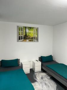een witte kamer met 2 bedden en een raam bij Pension Gergert Gundelsheim in Gundelsheim