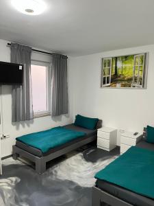a bedroom with two beds and a flat screen tv at Pension Gergert Gundelsheim in Gundelsheim