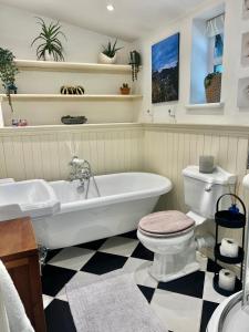 a bathroom with a tub and a toilet and a sink at Olive Tree Cottage in Rye