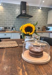 a table with a plate of cookies and a vase with a sunflower at Olive Tree Cottage in Rye