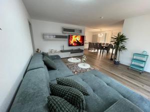 a living room with a blue couch and a tv at Deluxe Family Appartements Haem in Buchheim