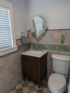 ein Badezimmer mit einem WC, einem Waschbecken und einem Spiegel in der Unterkunft 1926 Mediterranean Style Home with Heated Pool Sleeps 12 in West Palm Beach