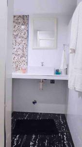 a white bathroom with a sink and a mirror at Moderno y nuevo departamento “Casa Blanca” in Trujillo