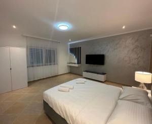 a bedroom with a large white bed and a flat screen tv at VILLA ORIJENT HM in Blagaj