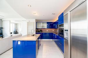 a kitchen with blue cabinets and a stainless steel refrigerator at Beachfront Luxury 2BR 2BA, Sleeps 6, Resort Access - Horizon by HomeStakes in Fort Lauderdale