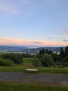 a park bench sitting in a field at sunset at Leilighet med utsikt ved bymarka in Trondheim