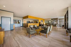 a lobby with chairs and tables and a kitchen at Suburban Studios Canon City in Canon City