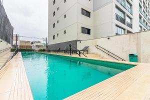 a swimming pool with blue water in front of a building at Loft Aconchegante no coração do Bom Retiro. in Sao Paulo