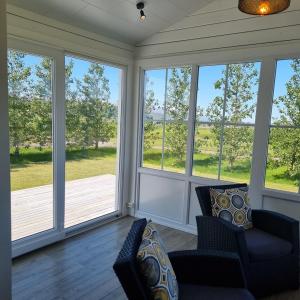 a living room with three large windows and a couch at Cosy cottage in the countryside in Þingeyjarsveit