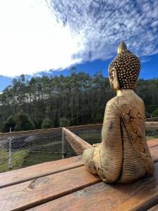 una estatua sentada en un banco mirando un campo en Refúgio Santa Helena - Domo Arigatô, en Salesópolis