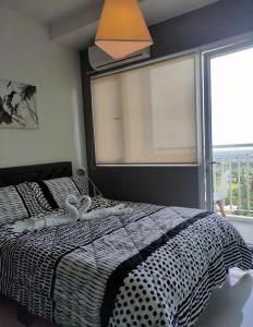 a bedroom with a black and white bed and a window at SMDC Wind residences in Tagaytay