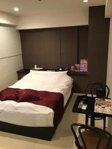 a bedroom with a bed and a table and chairs at ホテルルミエール in Narashino