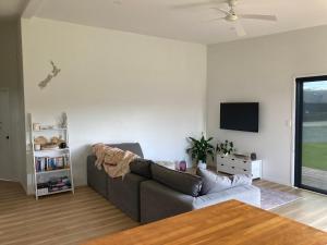 a living room with a couch and a tv at Harmony at the Heads in Mangawhai