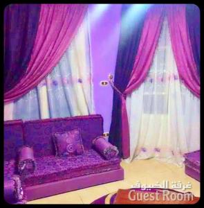 ein lila Sofa in einem Zimmer mit rosa Vorhängen in der Unterkunft Air-conditioned apartment - شقة مكيفه للايجار ف ميامي in Alexandria