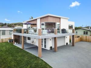 a large white house with a large deck at Hillside Haven House & Unit in Raglan