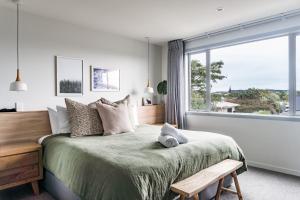 a bedroom with a bed with a large window at Hillside Haven House & Unit in Raglan