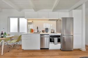 Silicon Valley Stay Apartments في سان كارلوس: مطبخ مع دواليب بيضاء وثلاجة ستانلس ستيل