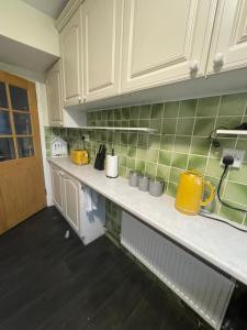 a kitchen with white cabinets and green tiles at Wardown Place - Spacious 3 Bed House available for short term or long term Rental in Luton