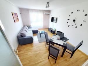 ein Wohnzimmer mit einem Tisch und einer Uhr an der Wand in der Unterkunft Aurora Apartman in Novi Beograd