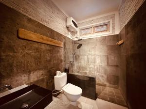 La salle de bains est pourvue de toilettes, d'un lavabo et d'une baignoire. dans l'établissement Volcano Terrace Bali, à Kintamani