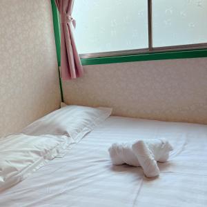Una toalla blanca puesta en una cama junto a una ventana en 花月荘 en Osaka