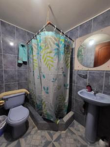 a bathroom with a shower curtain with a toilet and a sink at Como en casa in Latacunga