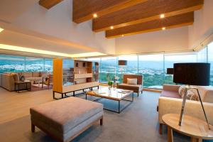 Elle comprend un salon doté de meubles et d'une grande fenêtre. dans l'établissement Marriott Tuxtla Gutierrez Hotel, à Tuxtla Gutiérrez