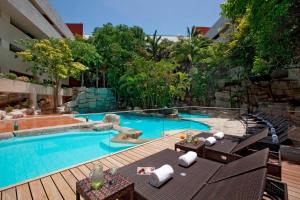 - une piscine avec une terrasse et des chaises à côté d'un bâtiment dans l'établissement Marriott Tuxtla Gutierrez Hotel, à Tuxtla Gutiérrez