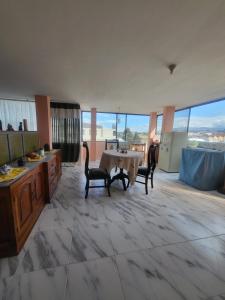 a kitchen with a table and chairs in a room with large windows at Como en casa in Latacunga