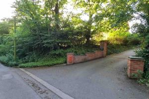 a brick driveway with a brick wall and trees at Hillfields Farm Barn - A Rural Equestrian Escape in Coventry