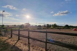 uma cerca num campo de terra com o sol no céu em Hillfields Farm Barn - A Rural Equestrian Escape em Coventry