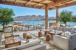 a patio with couches and tables and a view of the water at The Bodrum EDITION in Yalıkavak