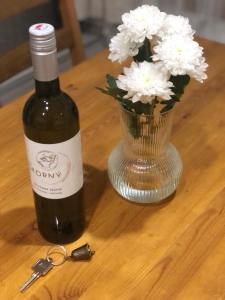 a bottle of wine next to a vase of white flowers at r E L L A x Studia Chvalovice (na Greenway Praha-Wien) in Chvalovice