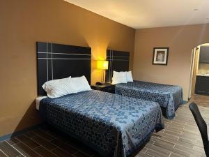 una habitación de hotel con 2 camas y una silla en Executive Inn & Suites, en Floresville