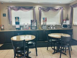 2 Tische und Stühle in einer Küche mit lila Vorhängen in der Unterkunft Executive Inn & Suites in Floresville