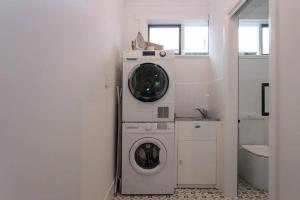 a bathroom with a washing machine and a washer at Morris Cottage Cumberland Park in Colonel Light Gardens