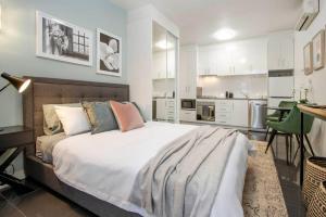 a bedroom with a large bed and a kitchen at Boho on Sussex North Adelaide in Adelaide