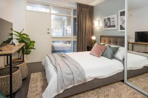 um quarto com uma cama com lençóis brancos e almofadas em Boho on Sussex North Adelaide em Adelaide