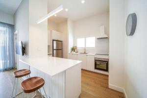 a white kitchen with a counter and two stools at The Retreat Plympton in Plympton