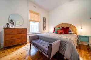 Schlafzimmer mit einem Bett, einer Kommode und einem Spiegel in der Unterkunft Il Cappano Rosa Henley Beach in Grange