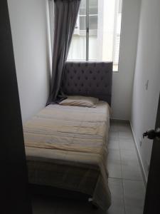 Apartahotel في إباغويه: سرير صغير في غرفة صغيرة مع نافذة