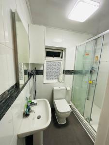 a bathroom with a toilet and a sink and a shower at Warwick Avenue Residency in Northolt