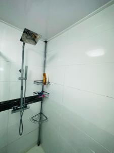 a shower in a room with white tiles at Warwick Avenue Residency in Northolt
