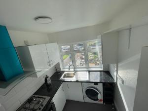 a small kitchen with a sink and a washing machine at Warwick Avenue Residency in Northolt
