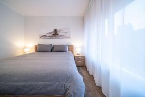a white bedroom with a bed and two lamps at Emerald on Gover Street in Bowden