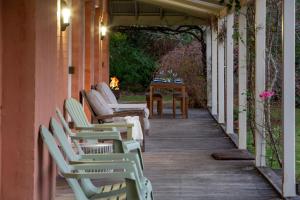a row of chairs sitting on a porch with a fireplace at Good Dog Hill Homestead in Bellawongarah